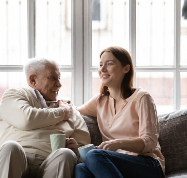 Happy older man and adult daughter drinking tea together