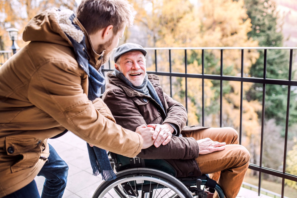 elderly-father-in-wheelchair-laughing-with-son