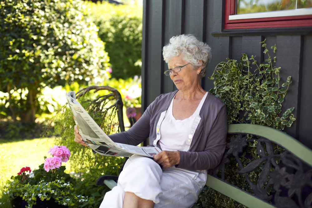 relaxed-old-woman-reading-newspaper-in-her-garden