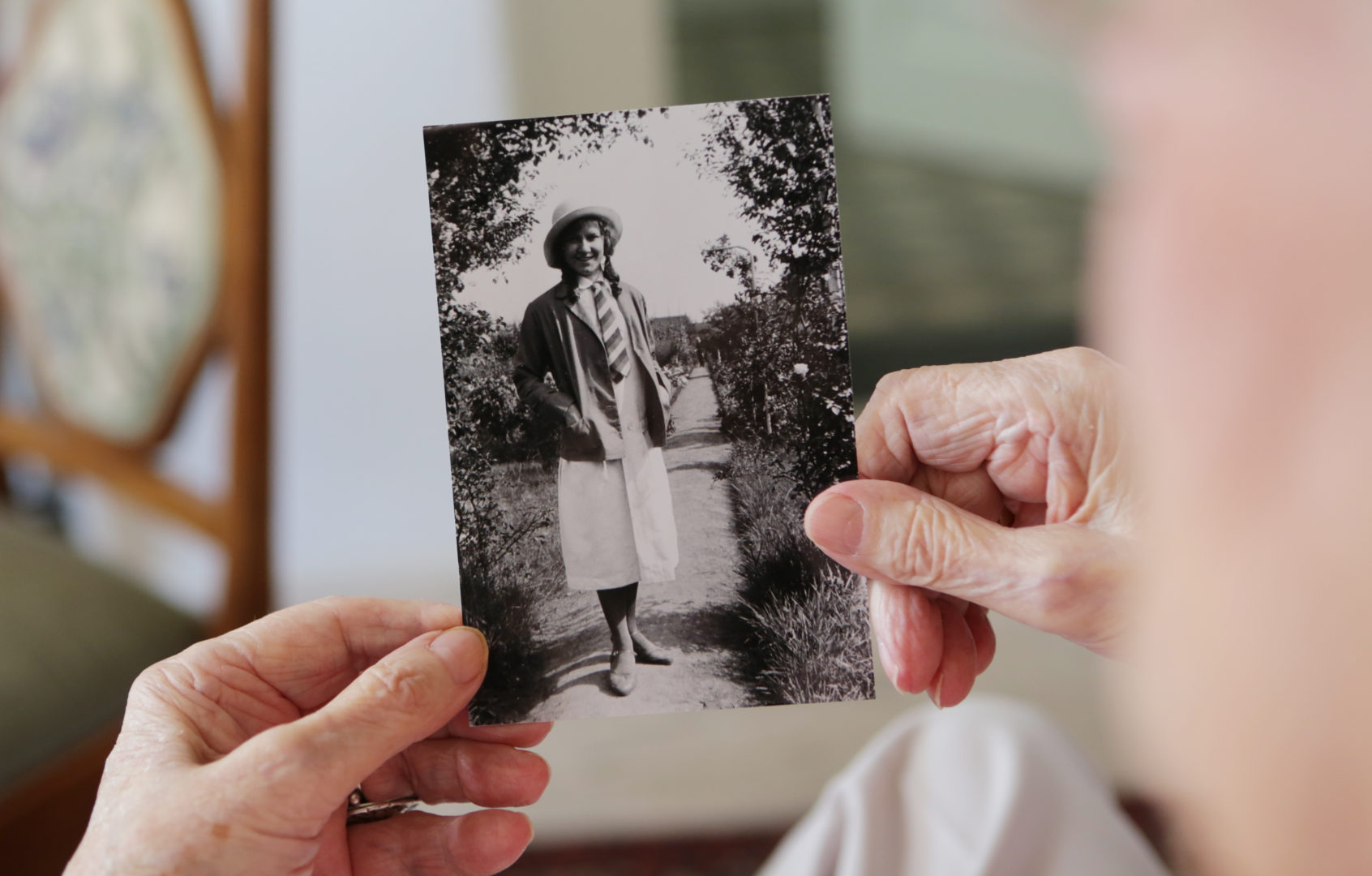 senior woman looking at young image of herself in her house