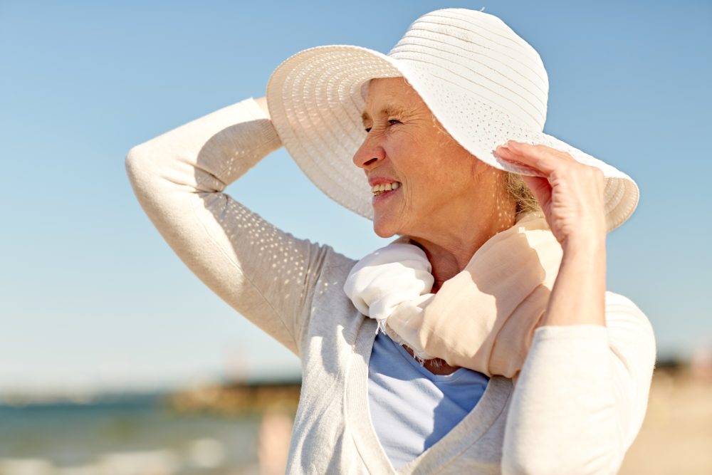 happy senior woman in sun hat on summer beach
