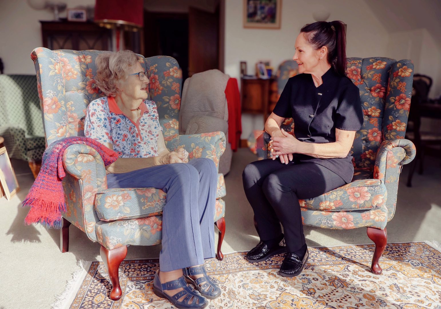 Elderly lady sat with her carer at home